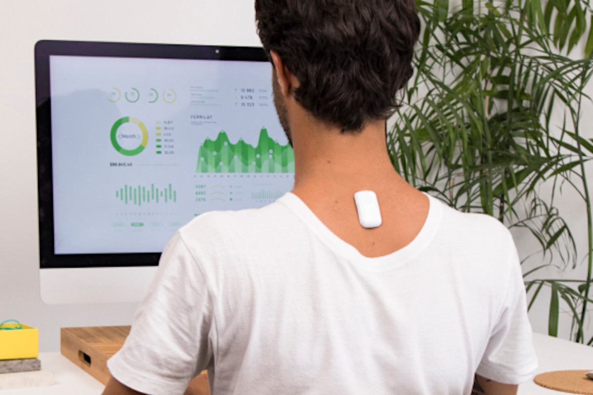 Man sitting up at desk with Upright Go 2 device on back of neck