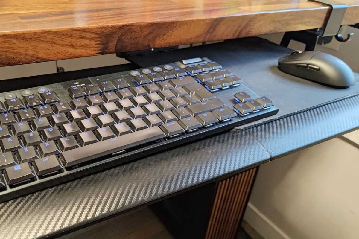 Hanging keyboard tray mounted on wooden desk table