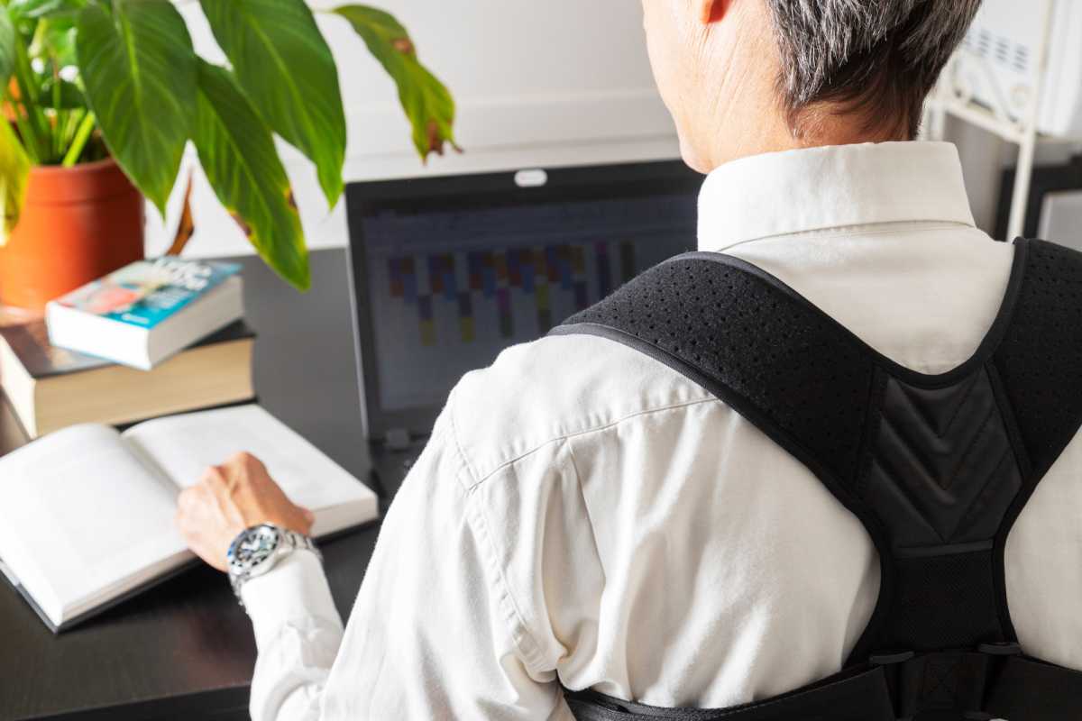 Man wearing posture corrector strap while working on his laptop